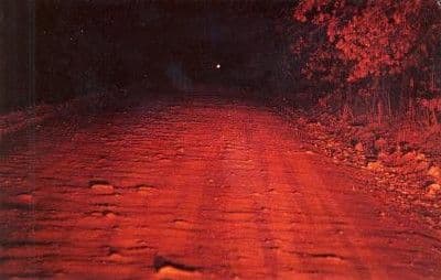 Chemin de terre isolé de nuit avec un point lumineux au loin, sur la Devil's Promenade